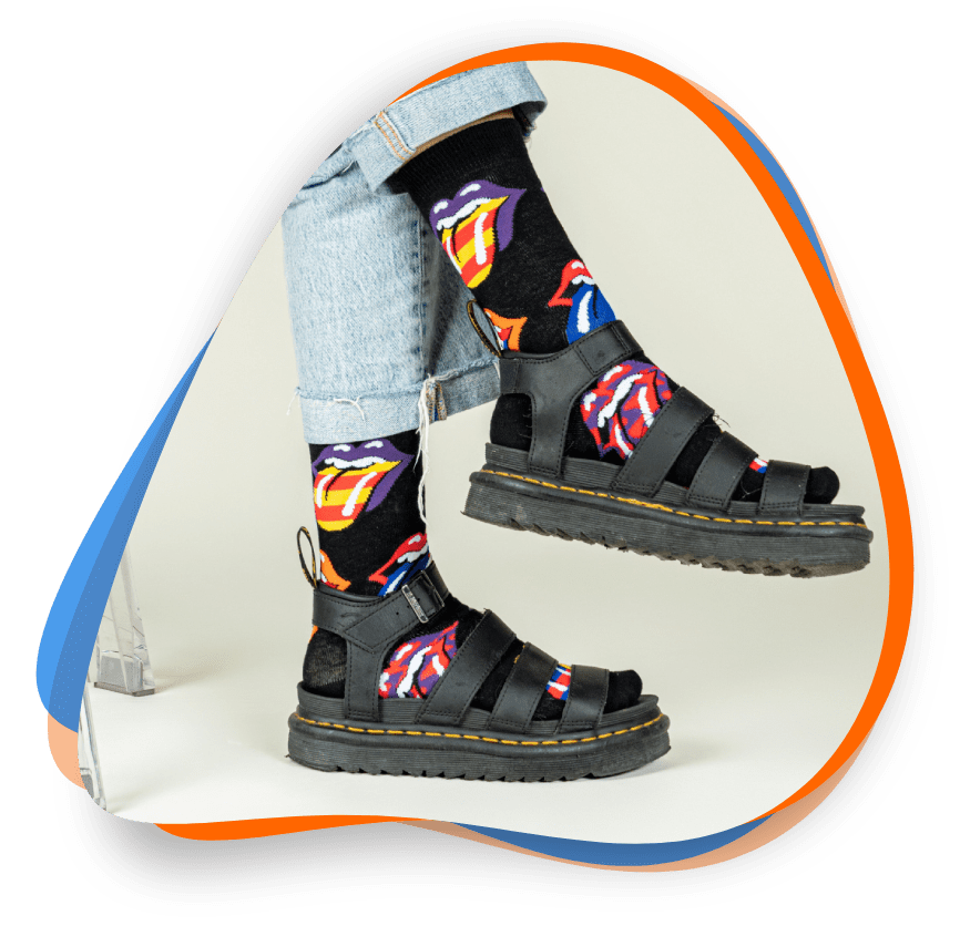 A person wearing sandals and socks with the image of superman on them.