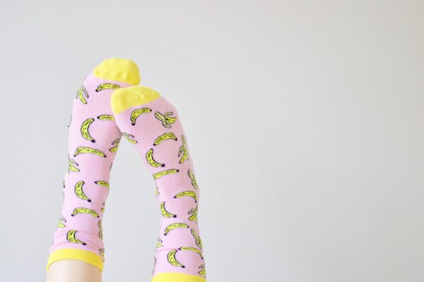 A person wearing pink and yellow socks with bananas.