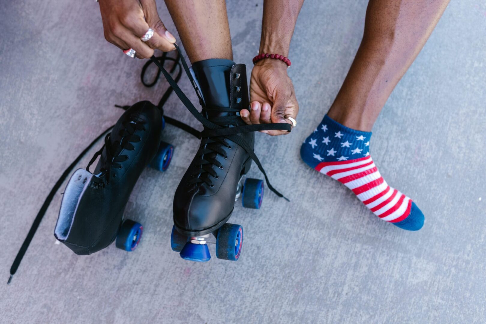 A person putting on roller skates with one foot and another leg in the other.