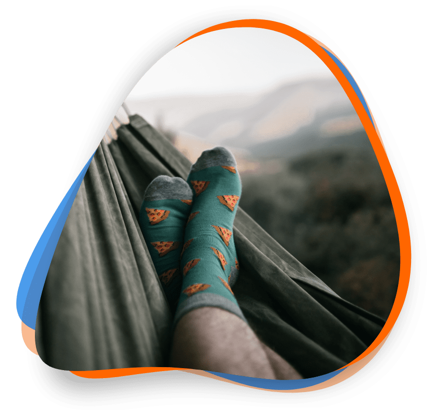 A person wearing socks is sitting in a hammock.