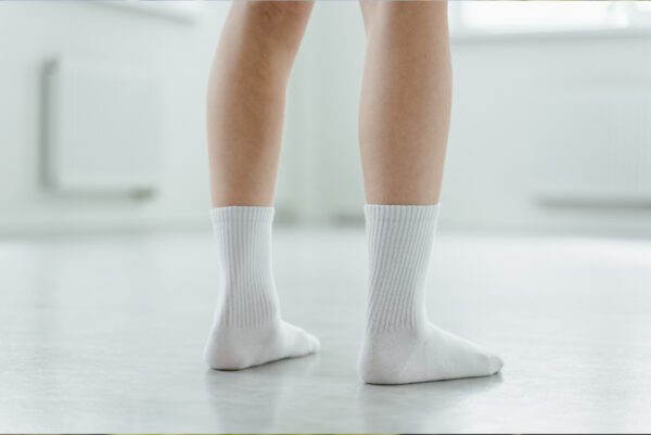 A person with white socks is standing on the floor.